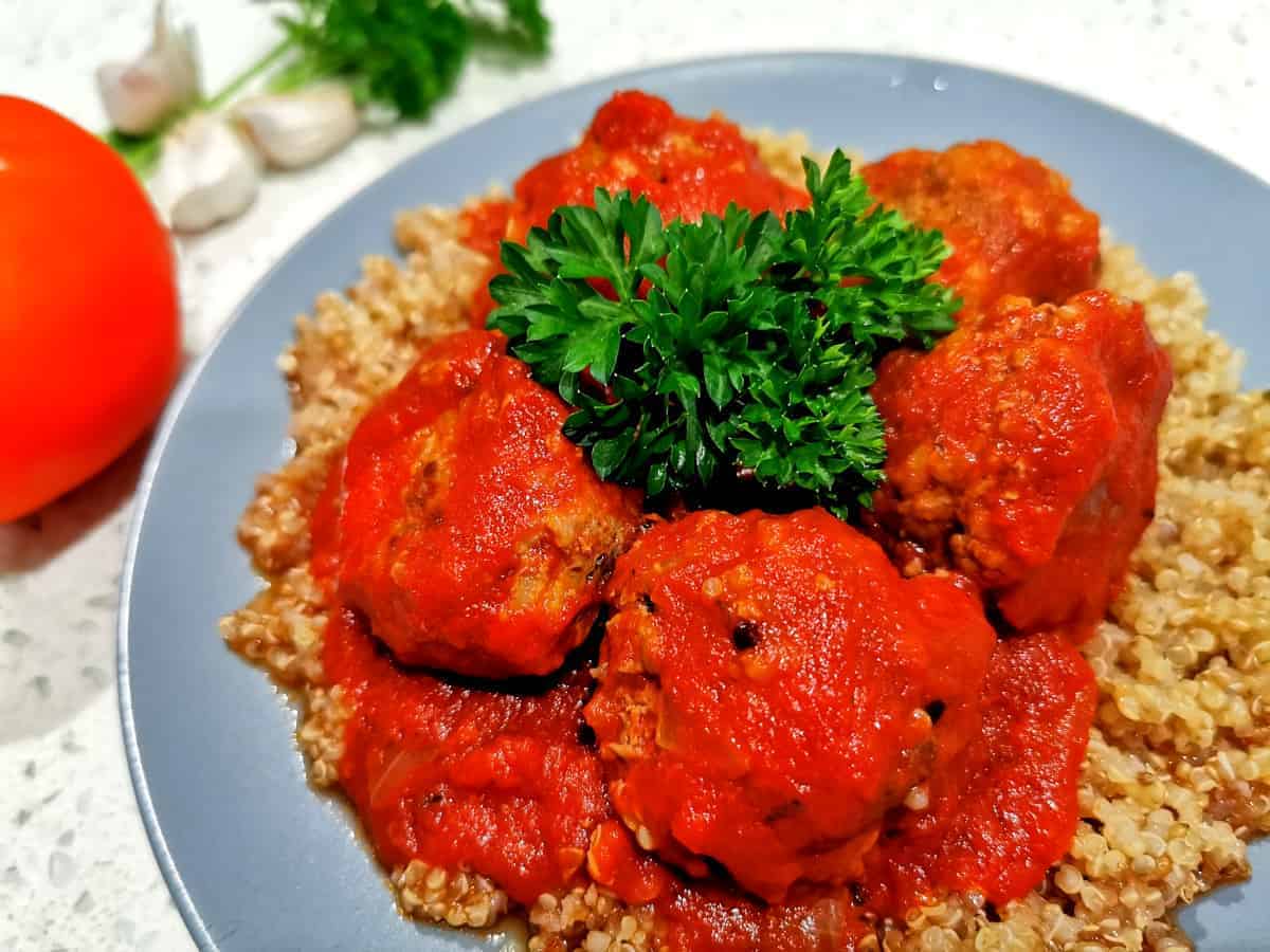 Gluten free meatballs served on a bed of quinoa and garnished with parsley