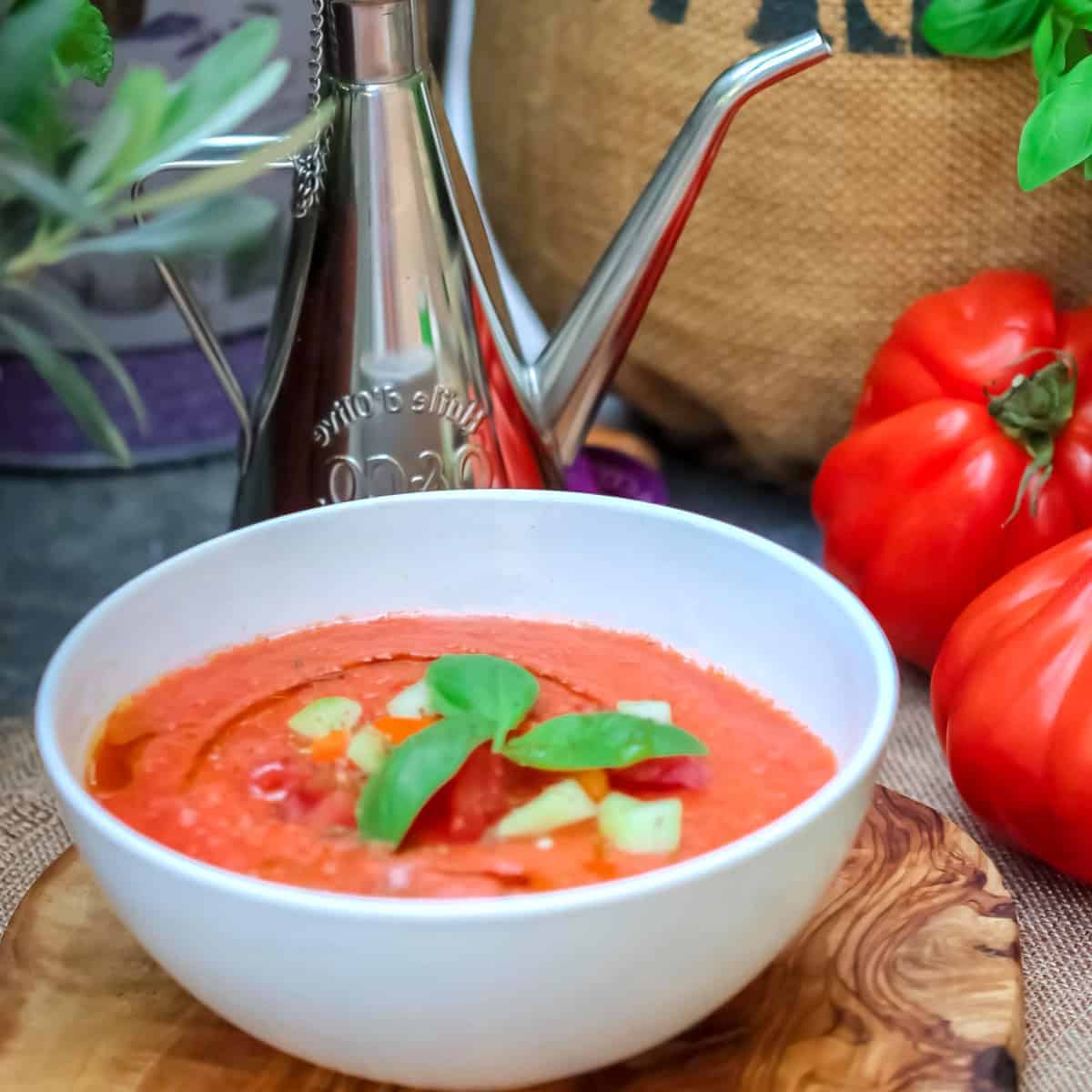 kick start soup served in a white bowl with tomatoes in the background