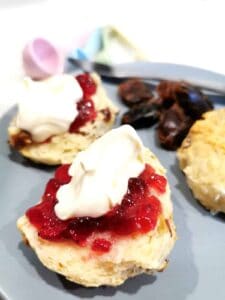 Date scones served on a plate and topped with raspberry jam and cream