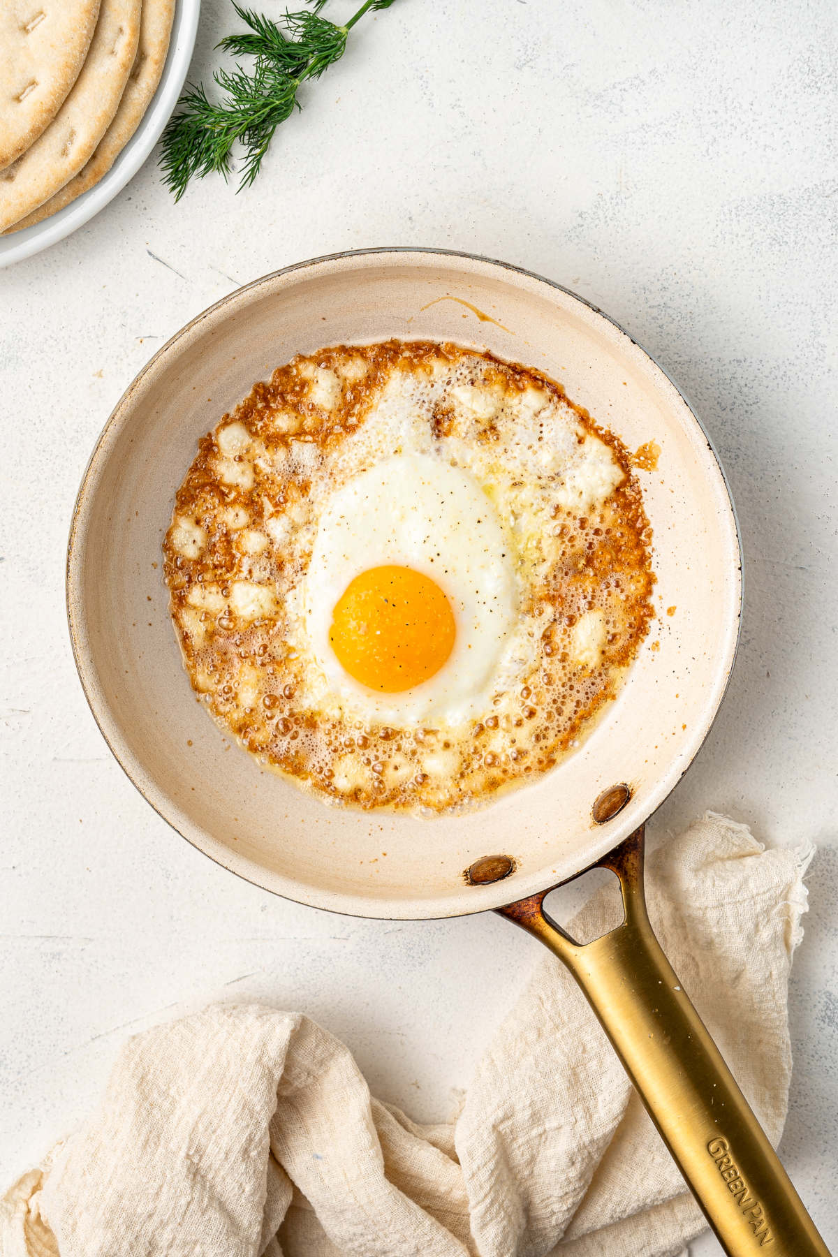 The eggs and feta fried in a pan resting on a kitchen counter, with salt and pepper.