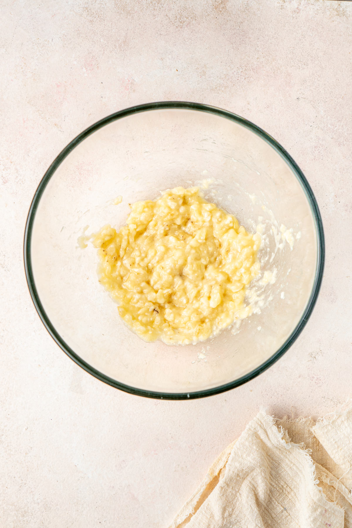 Mashed bananas in a glass mixing bowl.