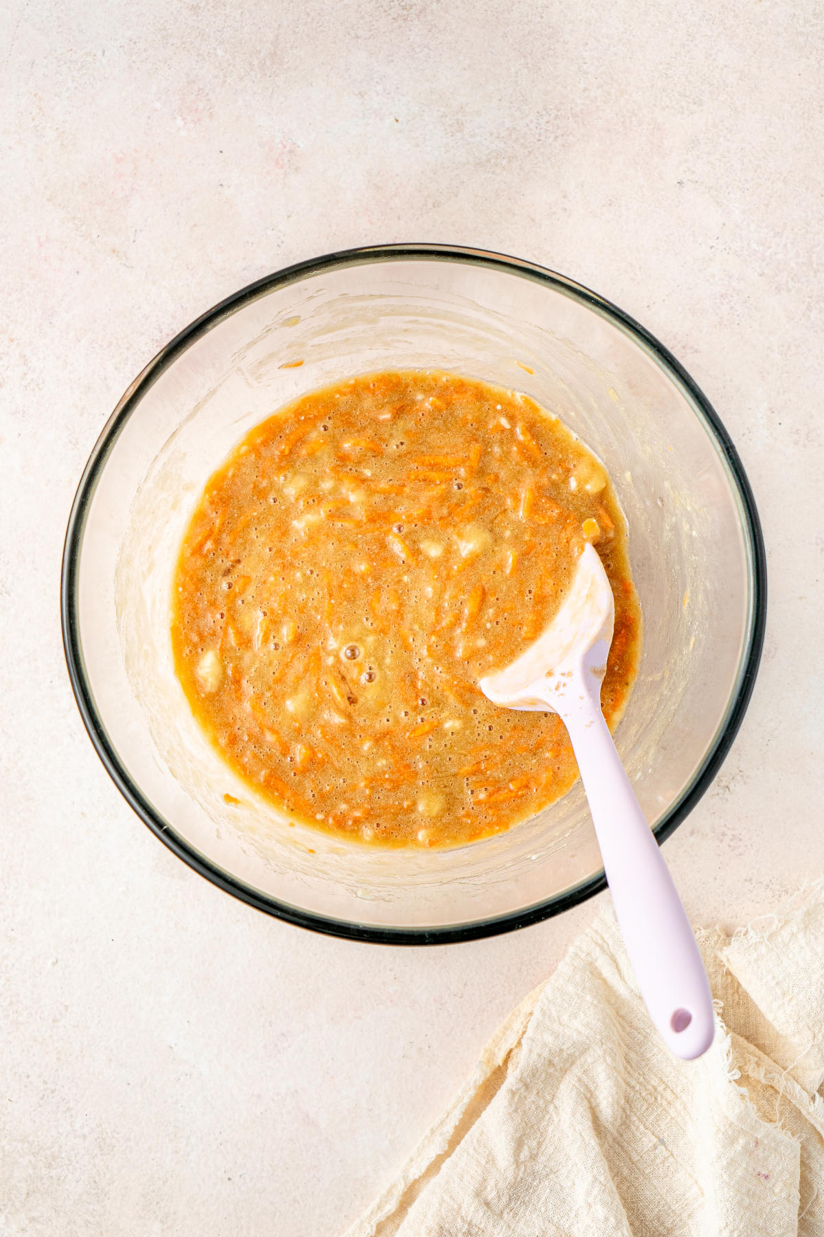A glass mixing bowl with all the wet ingredients for the muffins mixed together.