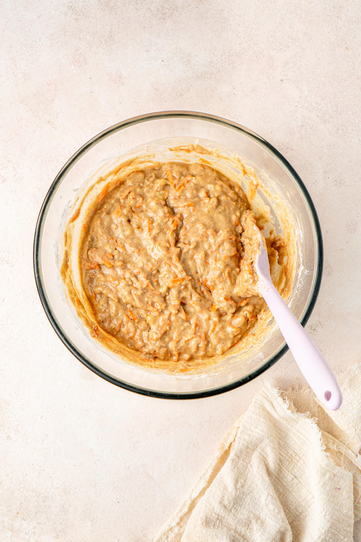 The mixing bowl, containing the mixed dry and wet ingredients and a white spatula.
