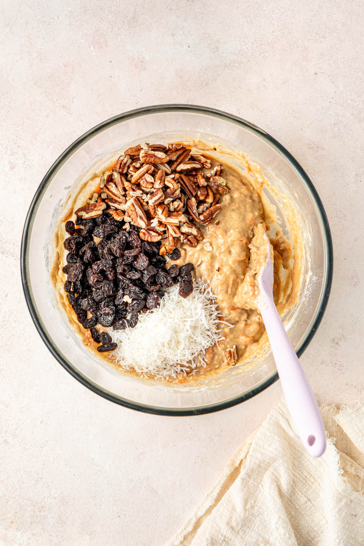 The mixed ingredients in their bowl with assed coconut, raisins and pecans ready to be mixed in.