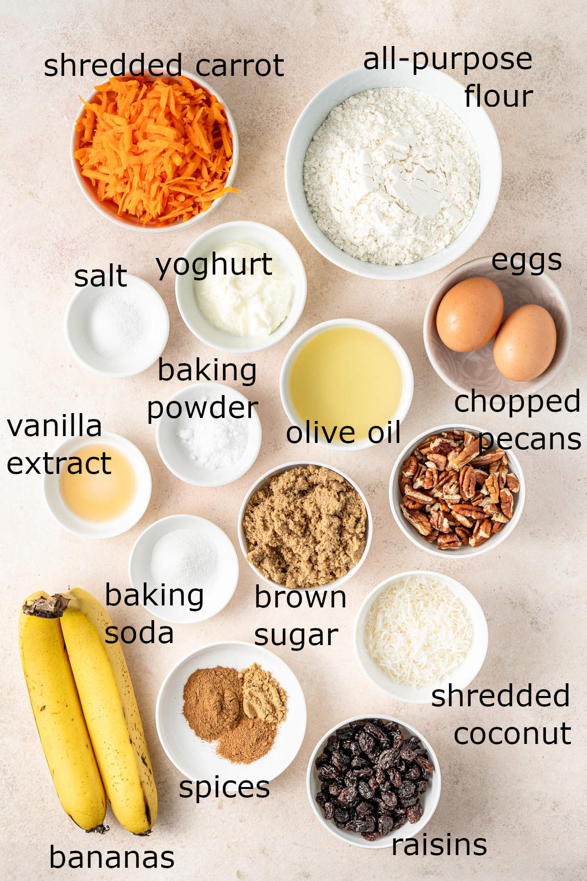The ingredients for the muffins laid out in small white bowls on a kitchen counter, each labelled.