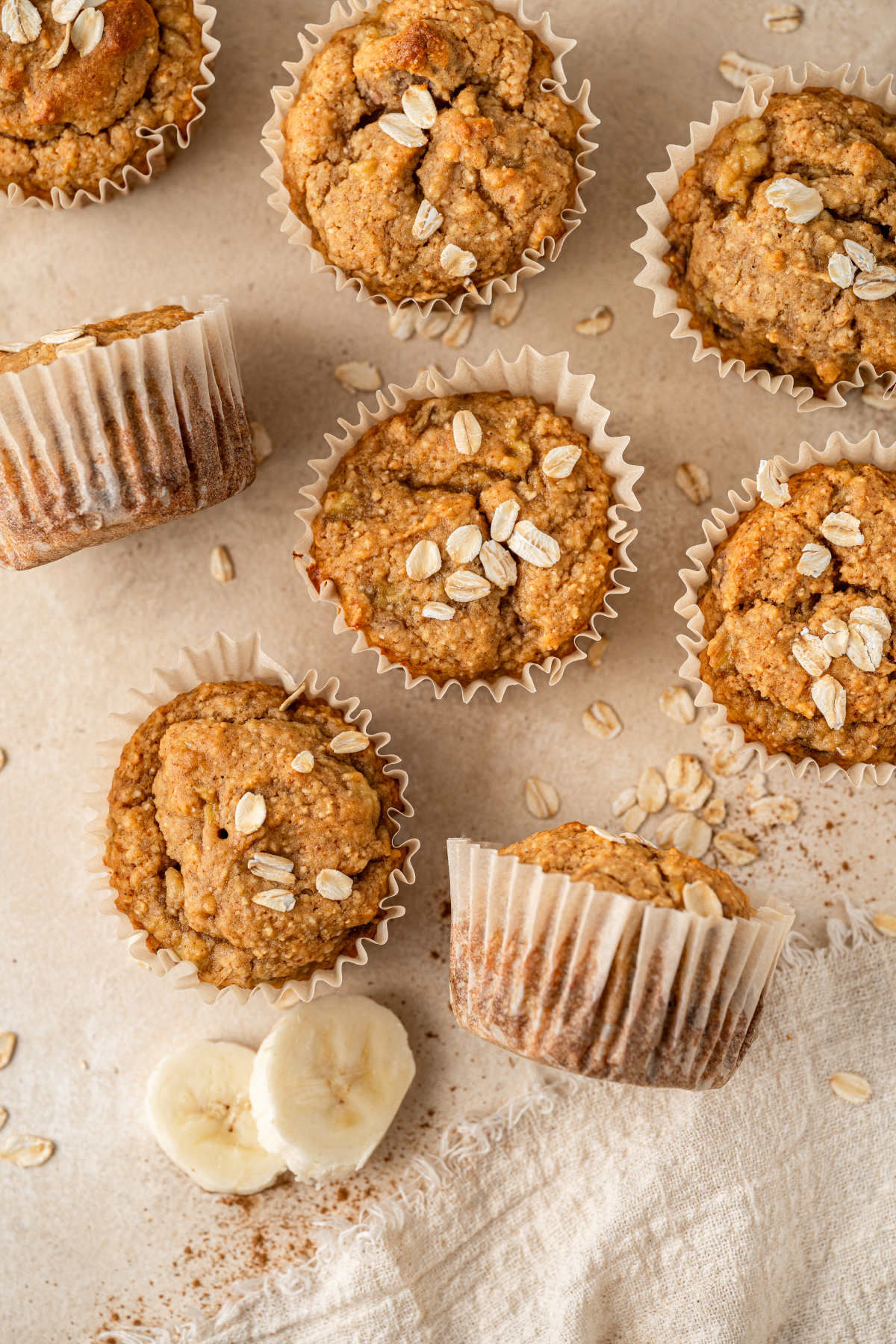 The cooled muffins, taken out of the tray and spread across the kitchen counter, sprinkled with oats.