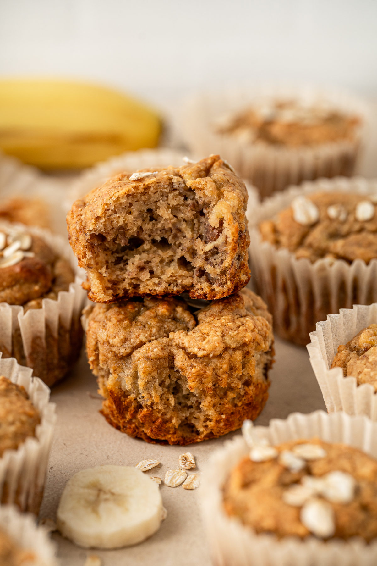 Two muffins stacked on top of each other, the top one having had a bite taken out of it.