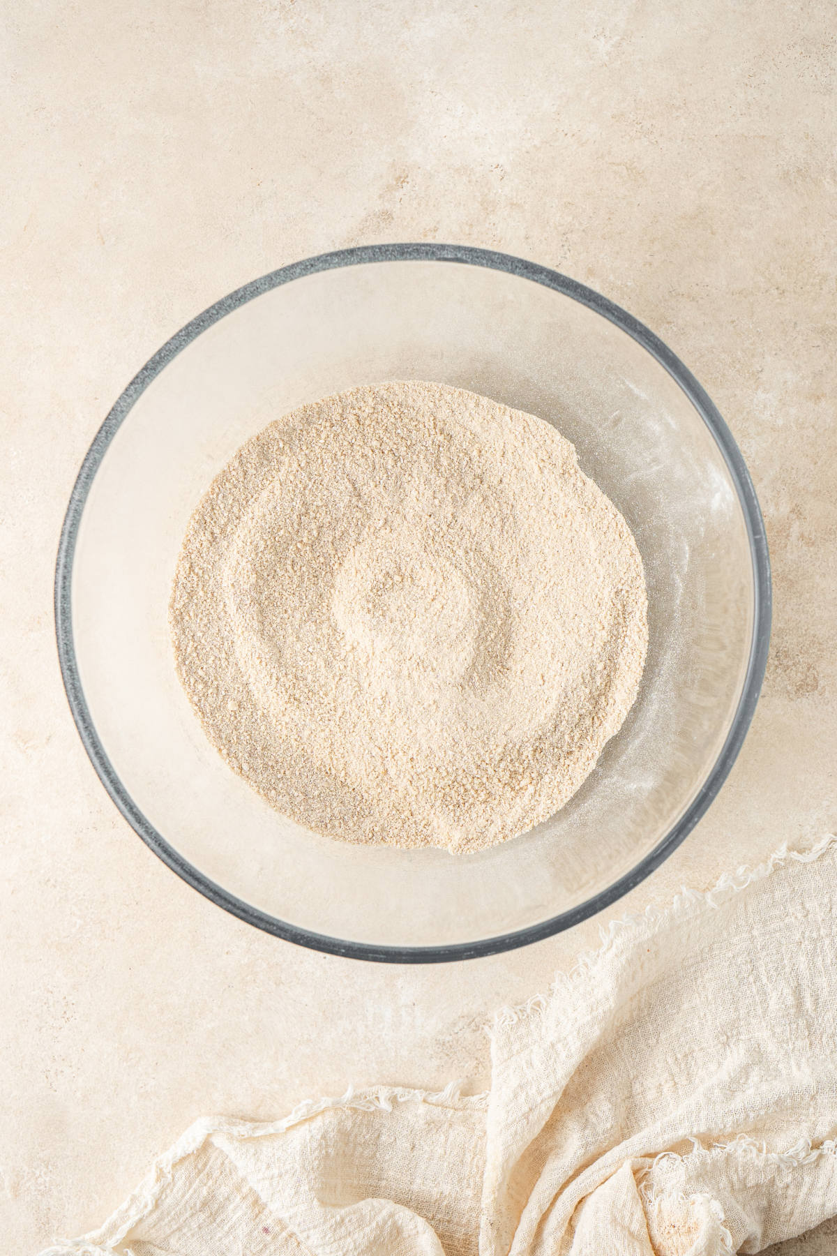 A glass mixing bowl of the dry ingredients of the muffins mixed together.