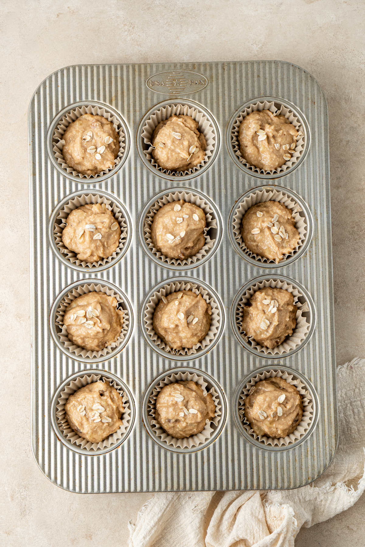 A muffin tray filled with paper muffin liners and the muffin batter.