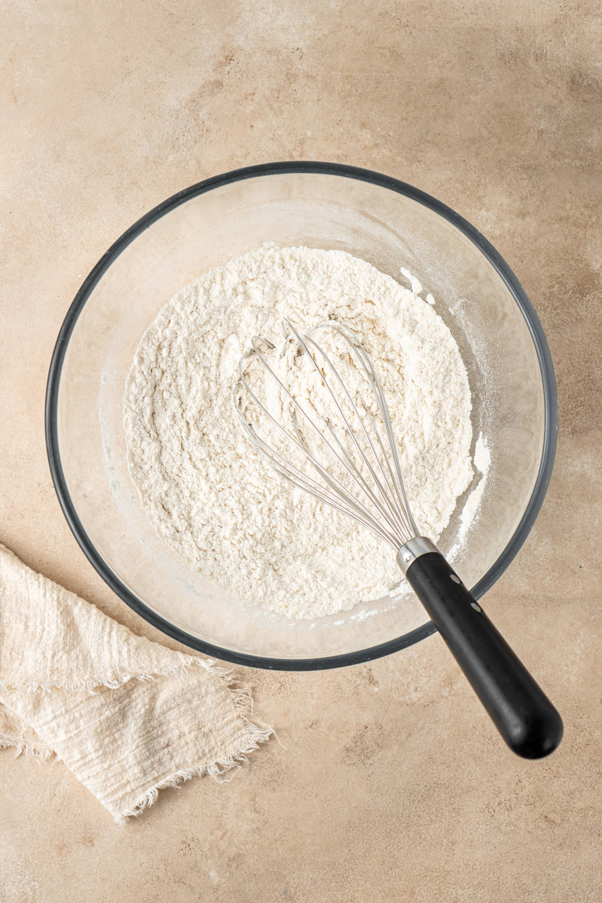 The dry ingredients for the cookies sitting in a glass mixing bowl with a whisk.