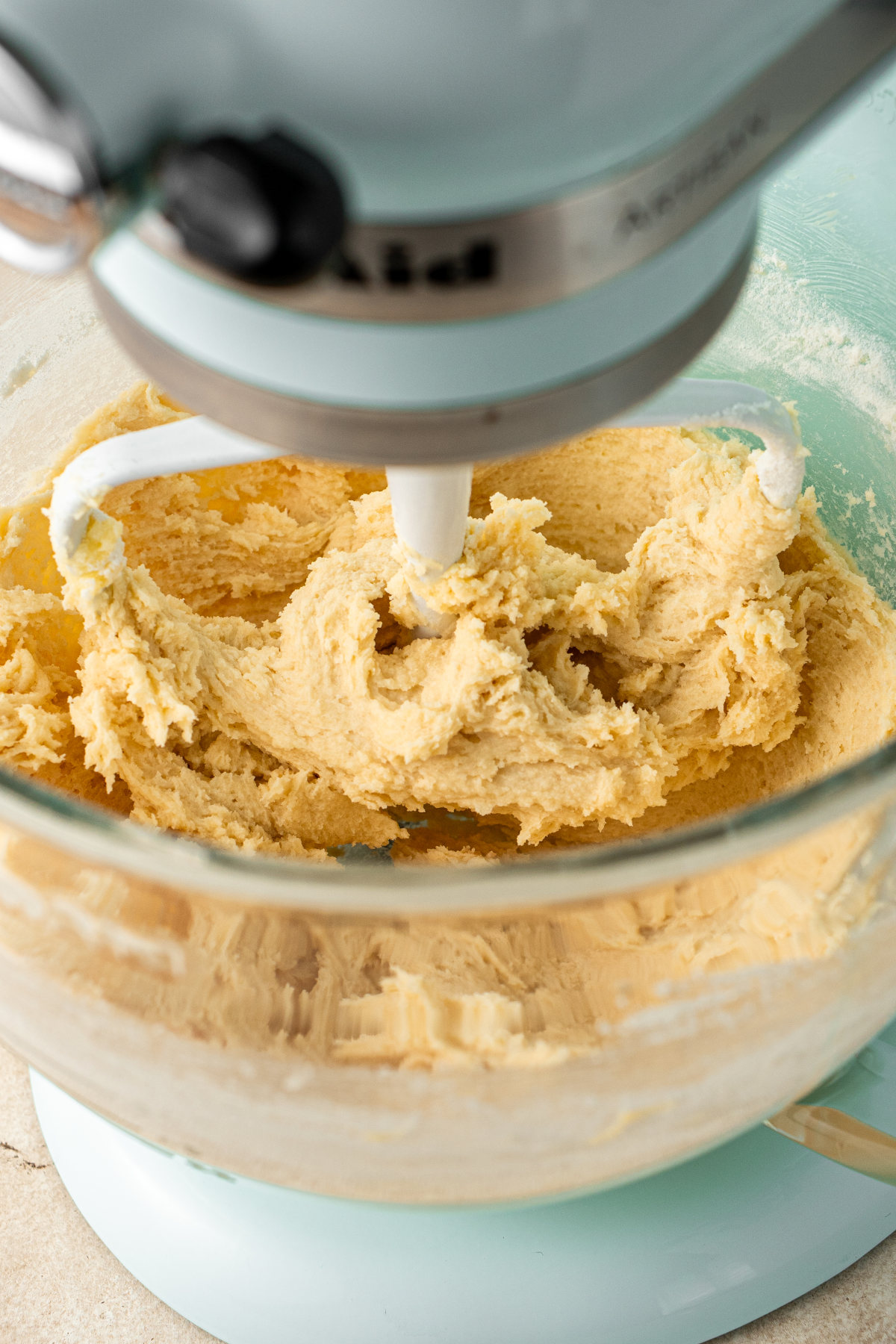 A close-up of the bowl of a stand mixer, with a thick dough in it.