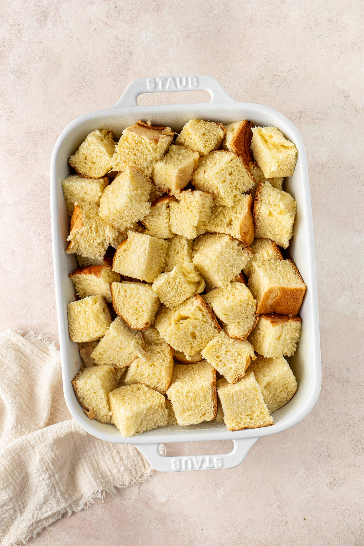 A casserole dish filled with chopped pieces of brioche sitting on a kitchen counter.