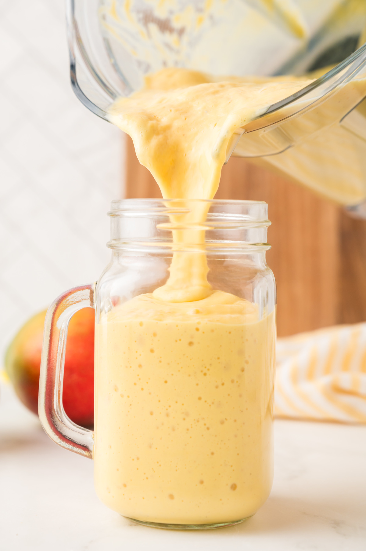 A glass mason jar being filled with milkshake straight out of the blender.