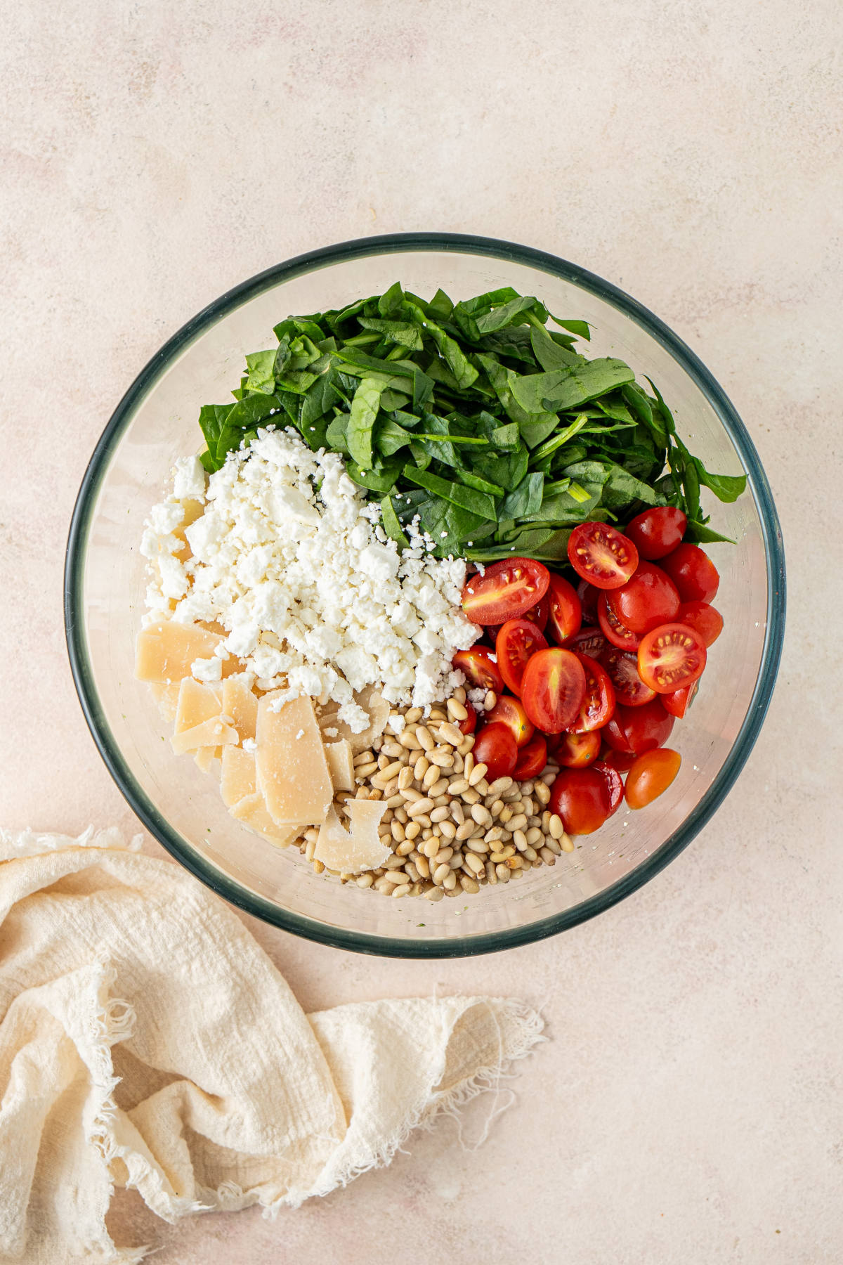A glass mixing bowl filled with the ingredients of our salad, ready to be mixed.