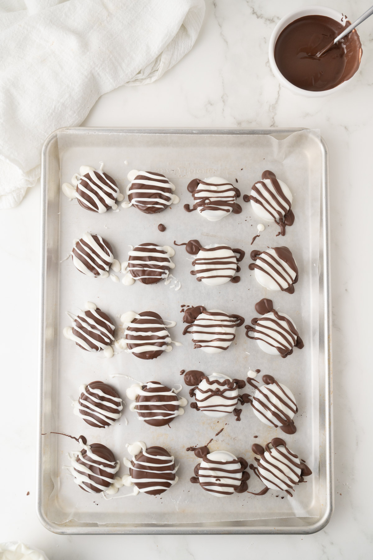 A baking tray lined with parchment, with 20 Oreos on it.