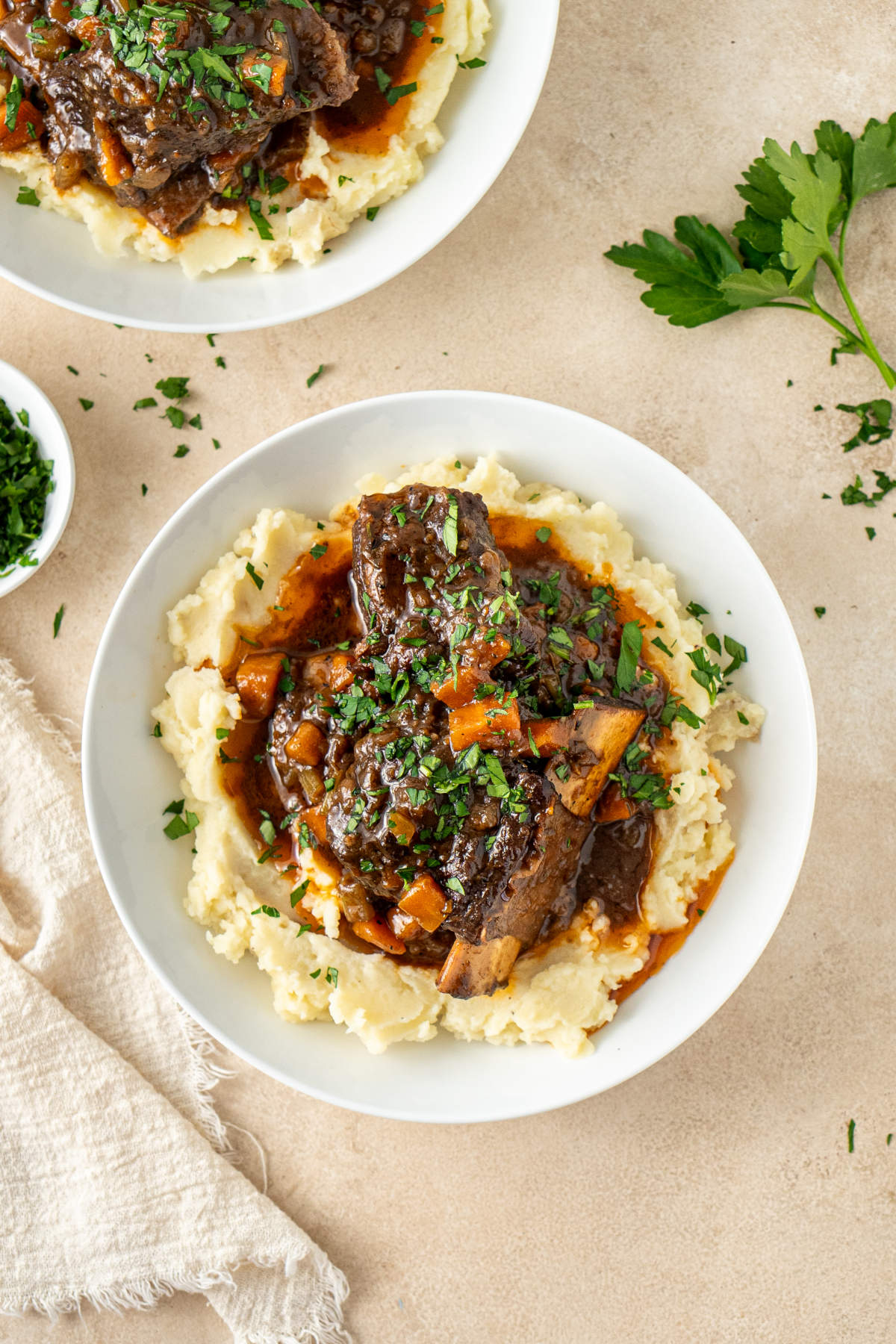 A plate of mashed potatoes over which has been served a helping of beef and its broth, garnished with parsley.