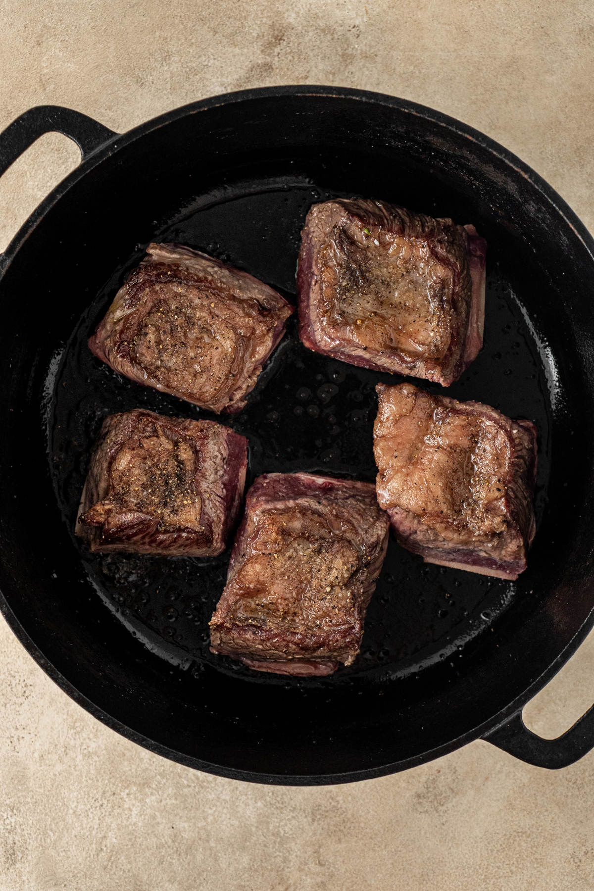 Five seared ribs in a cast iron pot.