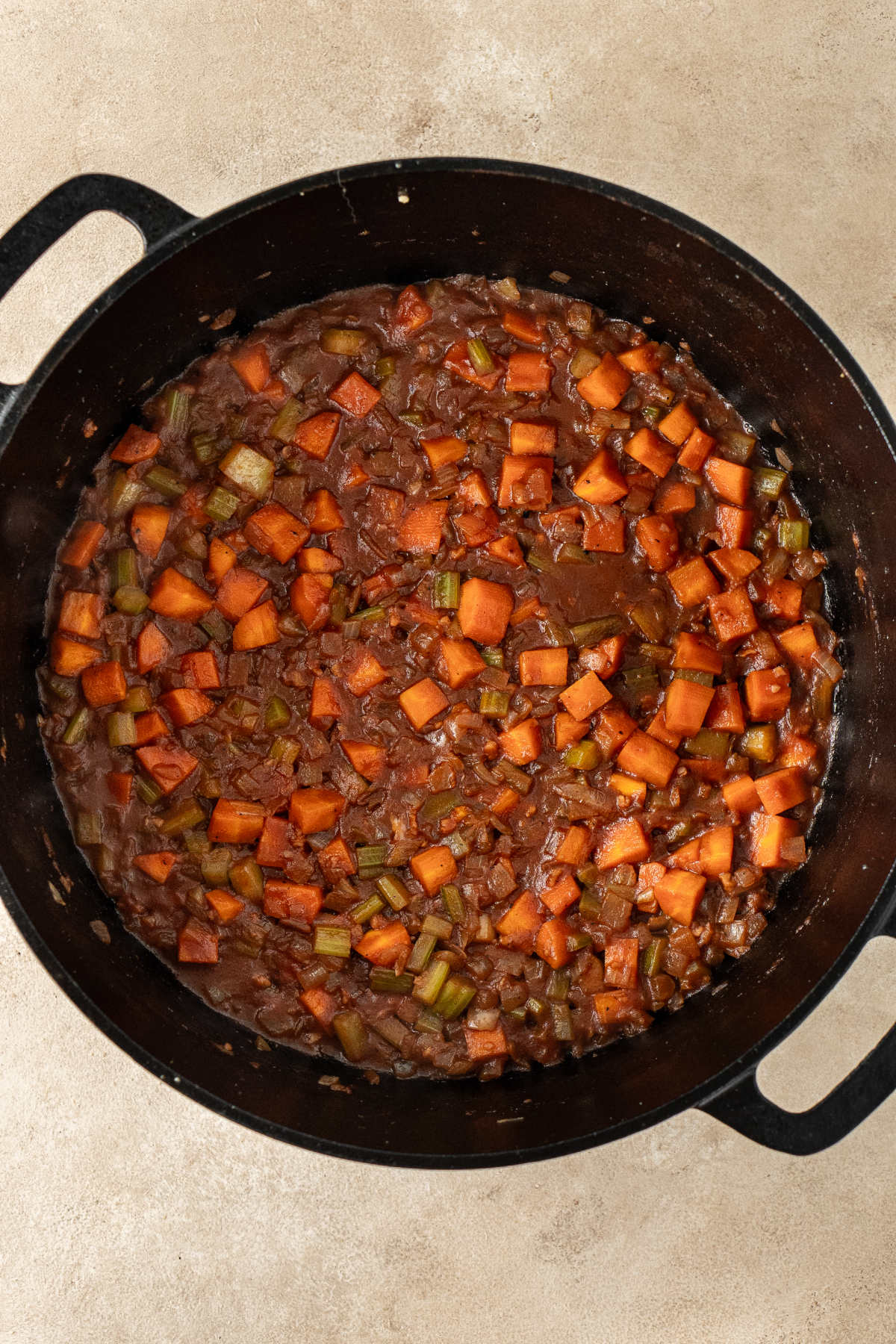 A pot of mirepoix with cooked tomato paste and red wine.
