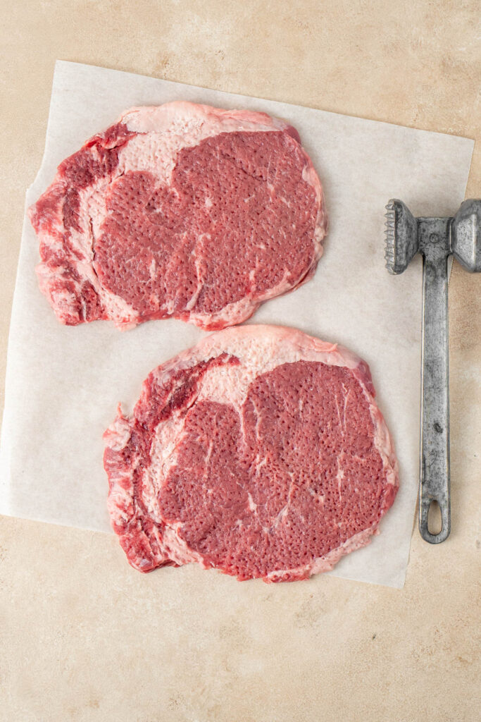 Tenderized beef with the tenderizer next to it.